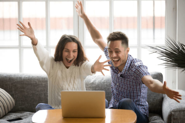 Two people excited as they view their laptop.